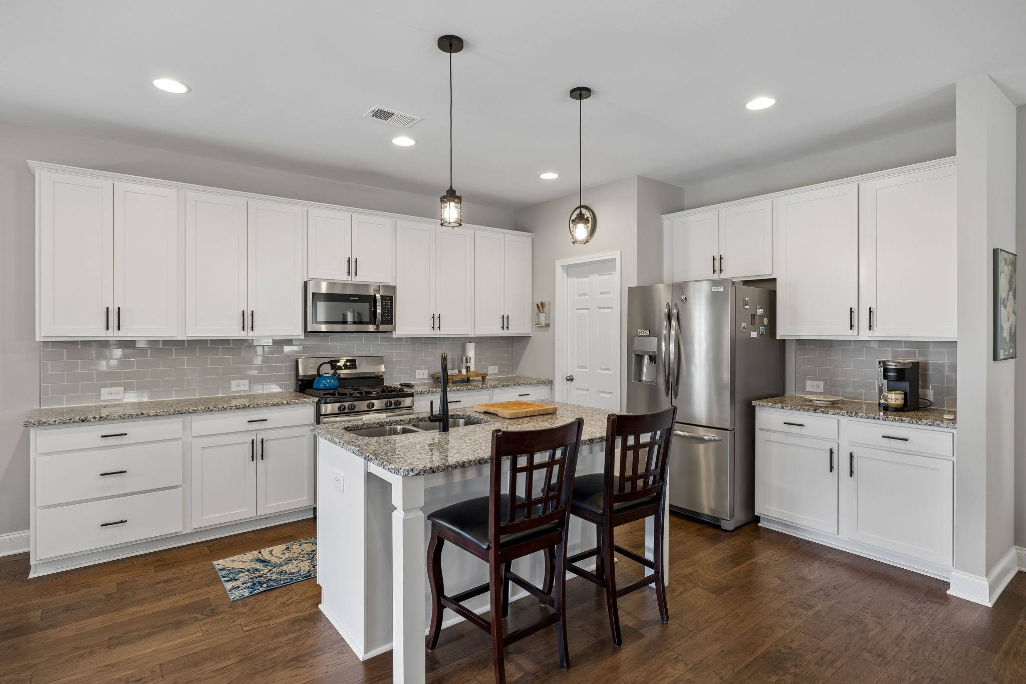 1017 Violet Street Spring Hill, TN 37174 - Photo 13 of 36 a kitchen with stainless steel appliances kitchen island granite countertop a dining table chairs refrigerator and microwave