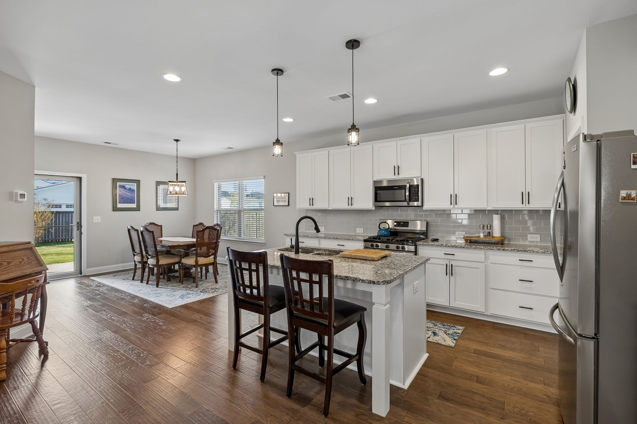1017 Violet Street Spring Hill, TN 37174 - Photo 7 of 36 a kitchen with stainless steel appliances kitchen island granite countertop a table chairs and a refrigerator