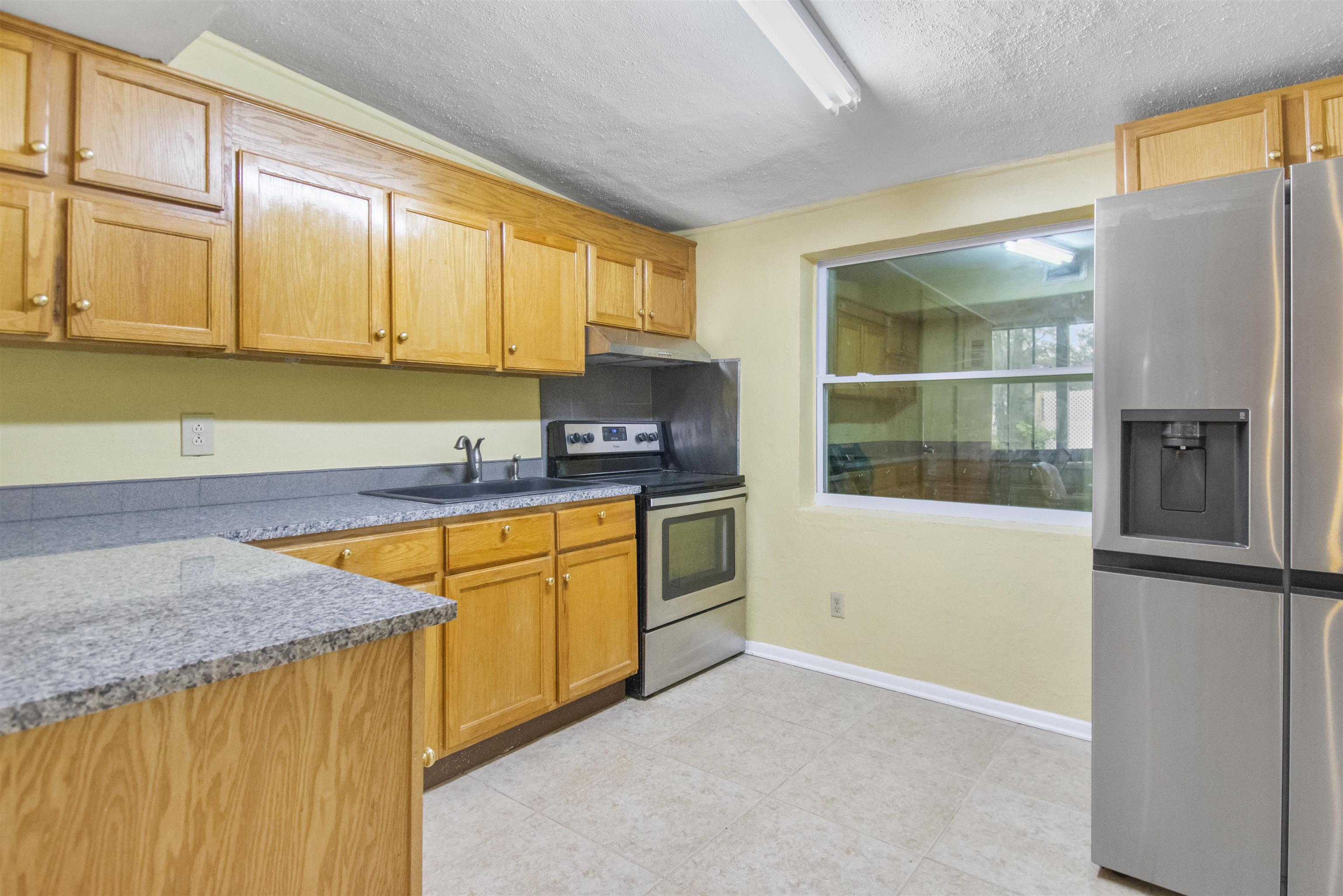 100 Spring Street St. Augustine, FL 32084 - Photo 8 of 21 a kitchen with stainless steel appliances granite countertop a refrigerator a stove and a sink with wooden floor