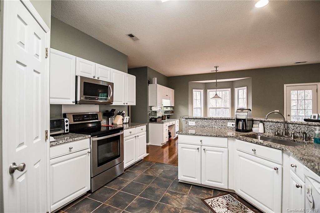 144 Comata Road Mooresville, NC 28117 - Photo 15 of 35 a kitchen with granite countertop white cabinets sink and stainless steel appliances