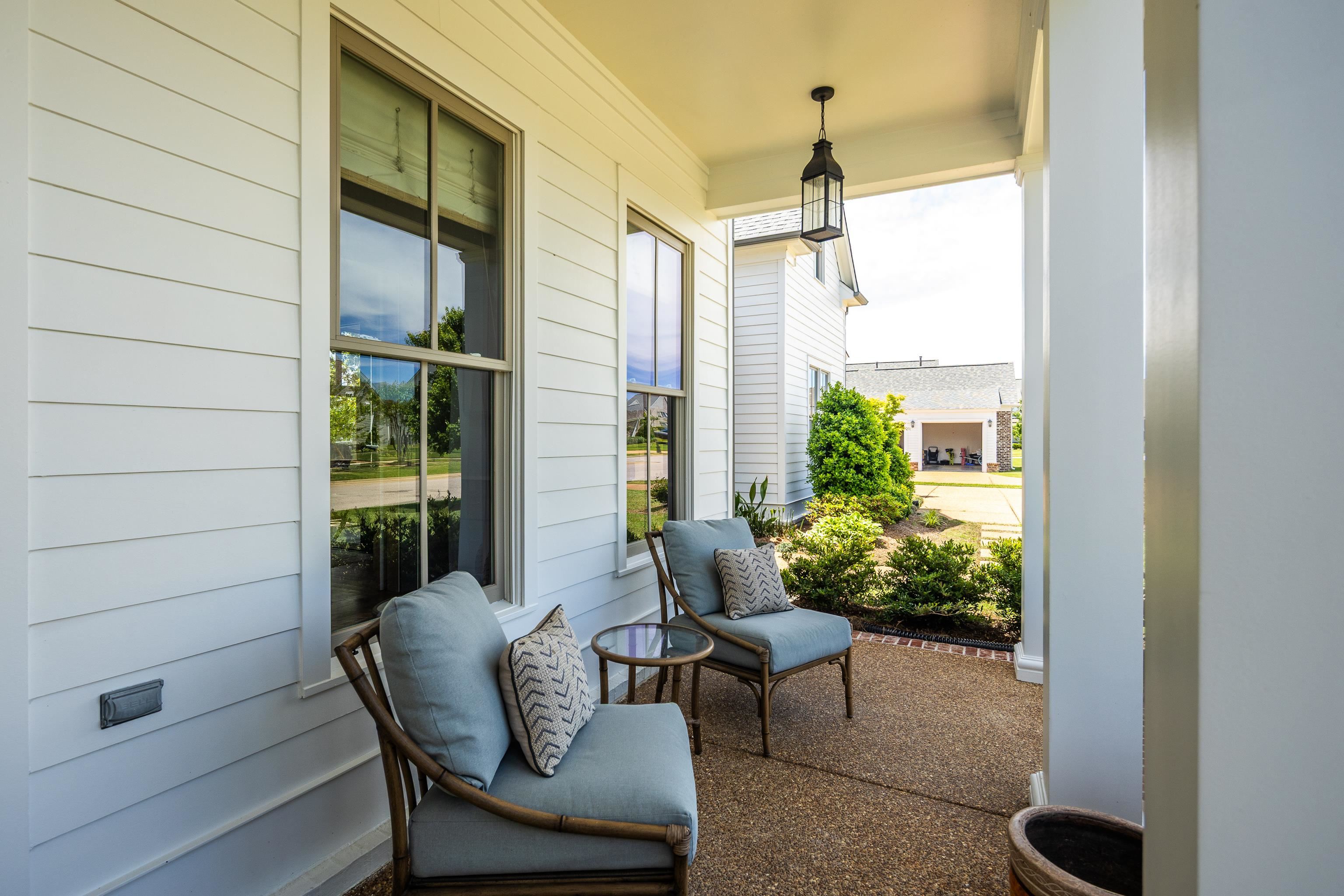 100 Sunflower View Road Piperton, TN 38017 - Photo 3 of 29 Inviting covered front porch with a lantern-style pendant light, exposed aggregate concrete flooring, and white paneled siding