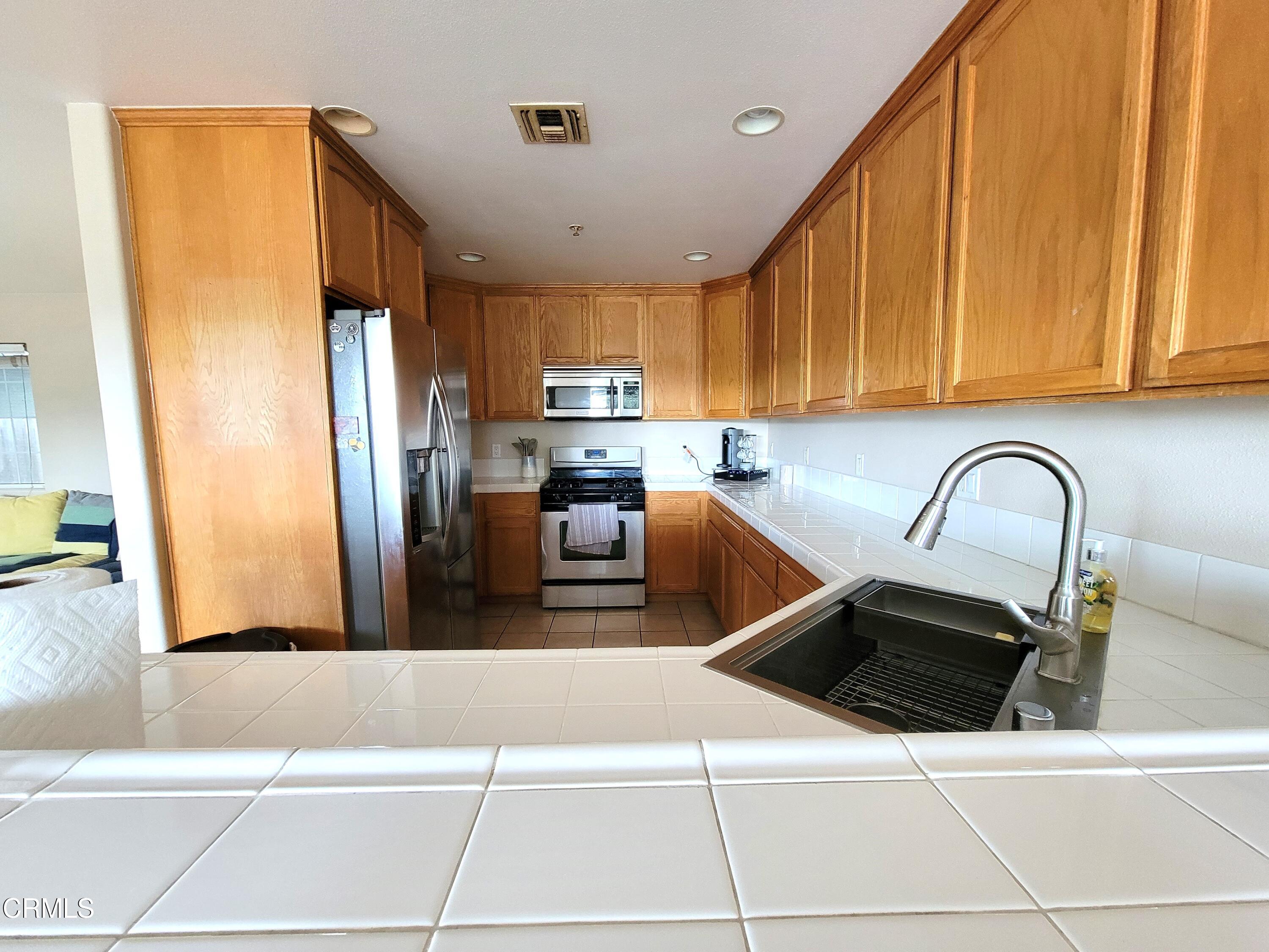811 Dunes Street Oxnard, CA 93035 - Photo 4 of 10 a kitchen with stainless steel appliances a refrigerator a sink a stove top oven a counter space and cabinets