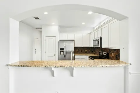 a kitchen with stainless steel appliances granite countertop a sink refrigerator and cabinets