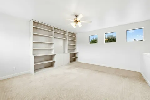 an empty room with a ceiling fan and window