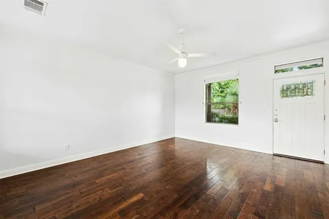 an empty room with wooden floor and windows