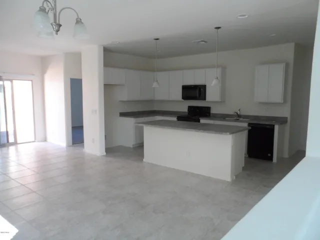 a kitchen with stainless steel appliances granite countertop a stove top oven a sink a refrigerator and white cabinets