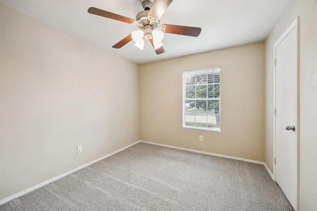 an empty room with a window and a fan