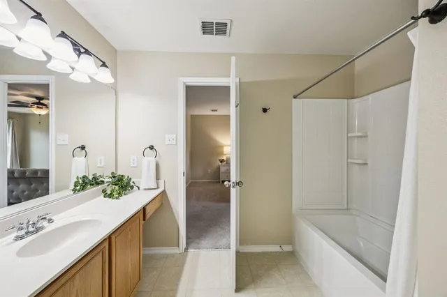 a spacious bathroom with a granite countertop sink a mirror and a bathtub