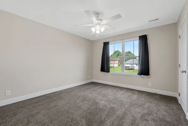 an empty room with windows and chandelier fan