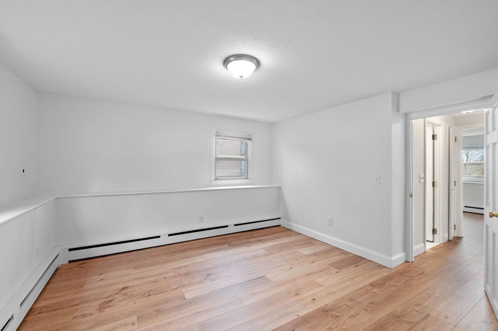121 Cambridge Road, Unit 2 Woburn, MA 01801 - Photo 11 of 23 an empty room with wooden floor and windows