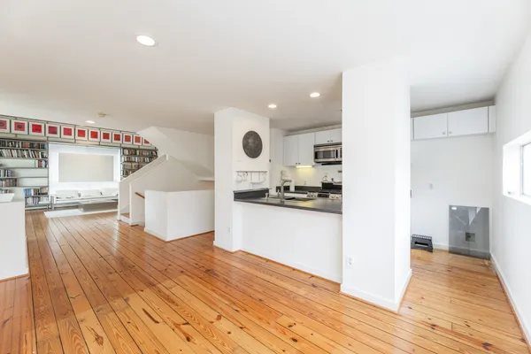 a view of a kitchen with kitchen island a sink wooden floor and stainless steel appliances