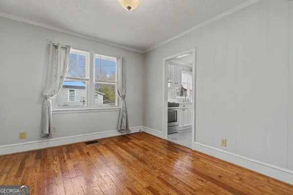 a view of empty room with wooden floor and fan