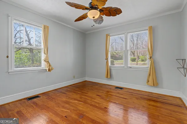 a view of an empty room with wooden floor and a window