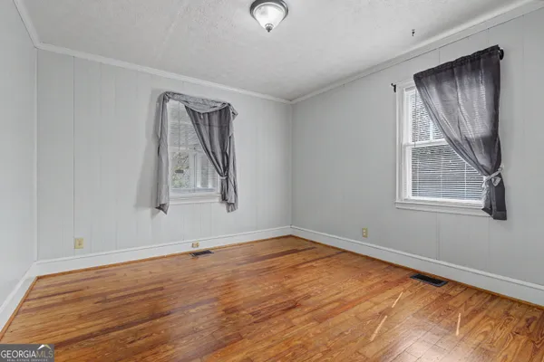 a view of an empty room with wooden floor and window