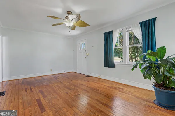 a view of an empty room with wooden floor and a window