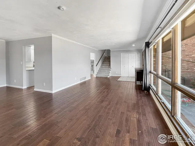 a view of a big room with wooden floor and windows