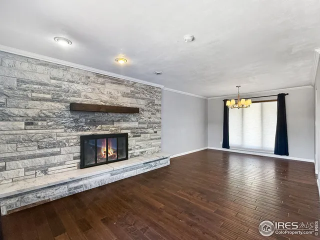 a view of an empty room with wooden floor fireplace and a window