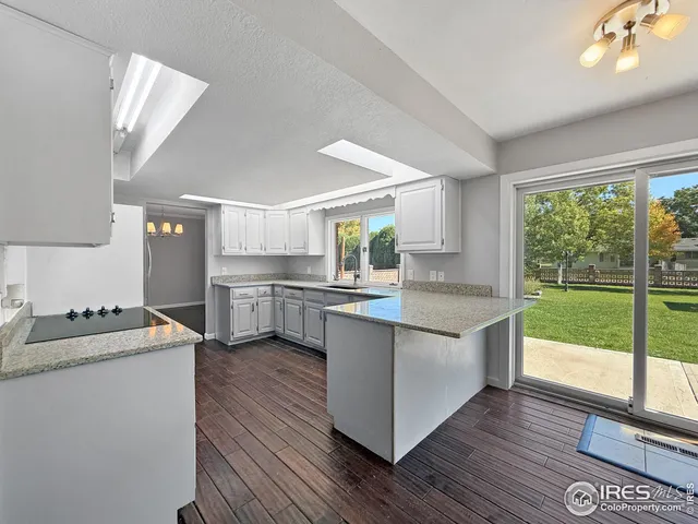 a kitchen with stainless steel appliances granite countertop a stove a sink dishwasher and a refrigerator with wooden floor