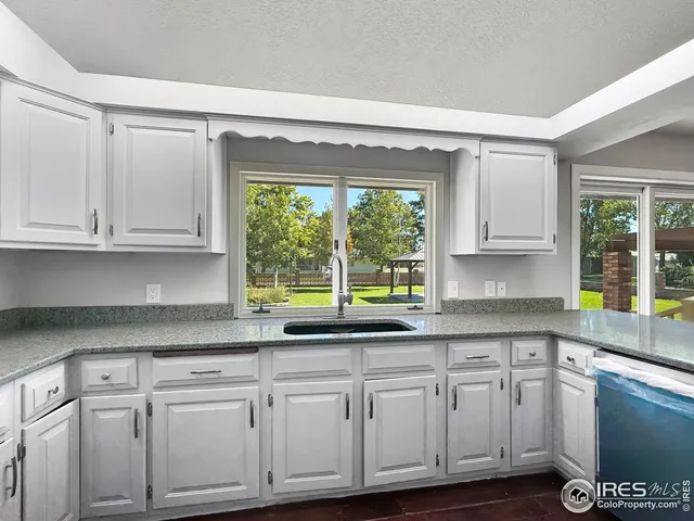 a kitchen with granite countertop white cabinets and a window