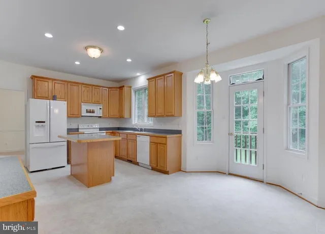 a open kitchen with a refrigerator a stove top oven a sink dishwasher and white cabinets with wooden floor