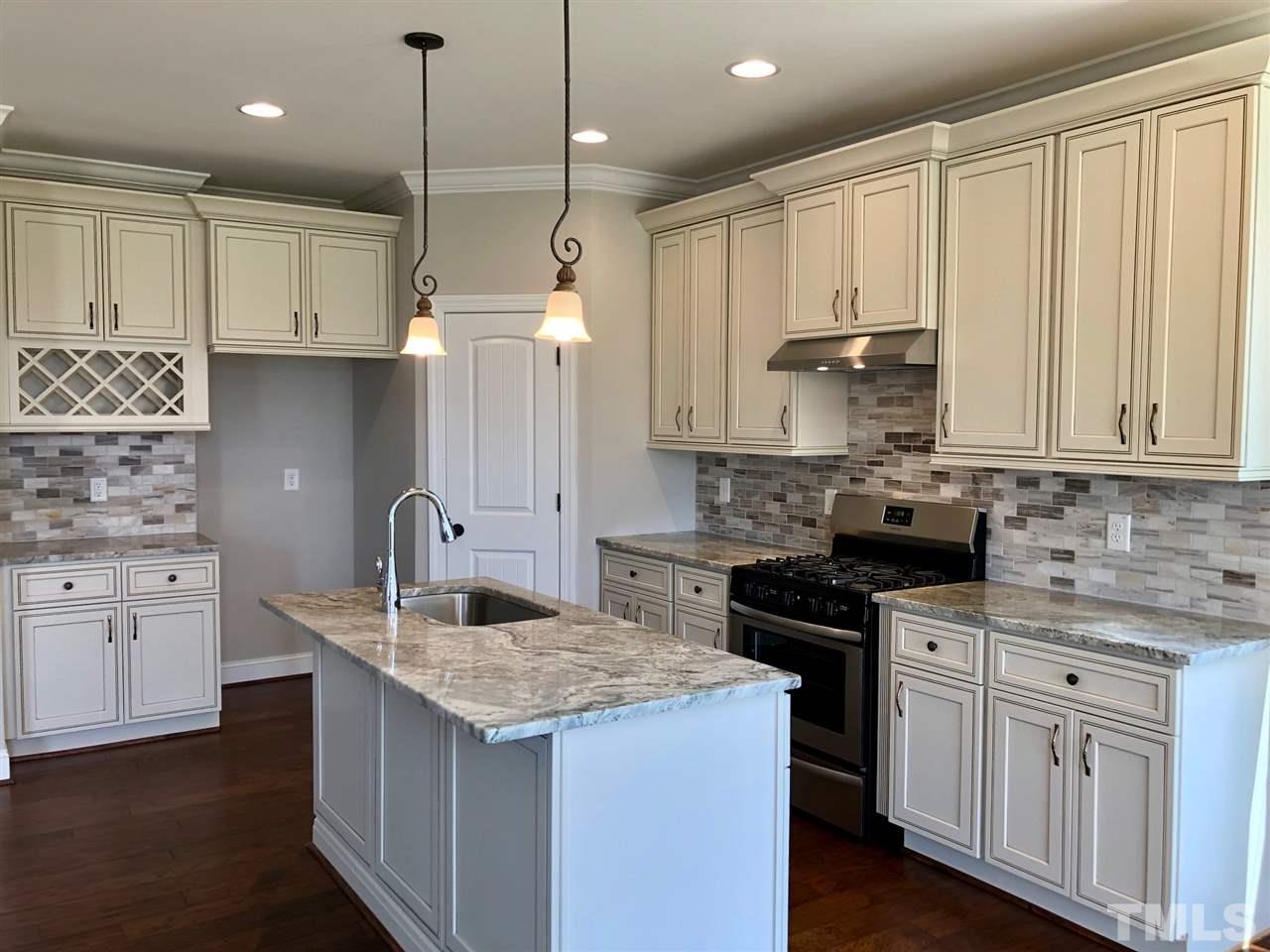 3717 Massey Ridge Court Raleigh, NC 27616 - Photo 5 of 24 a kitchen with kitchen island granite countertop a sink a stove and cabinets