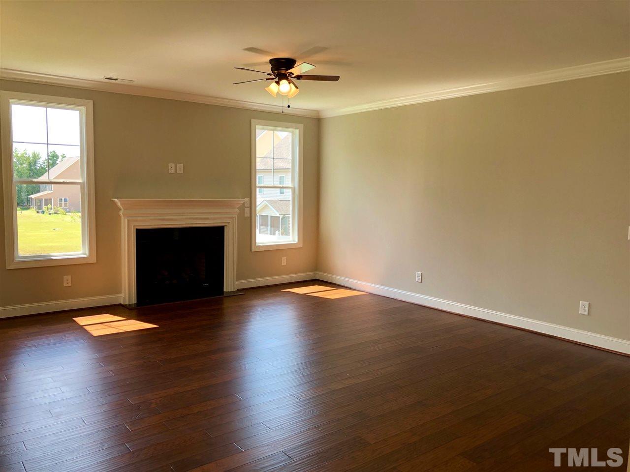 3717 Massey Ridge Court Raleigh, NC 27616 - Photo 9 of 24 an empty room with windows fireplace and wooden floor