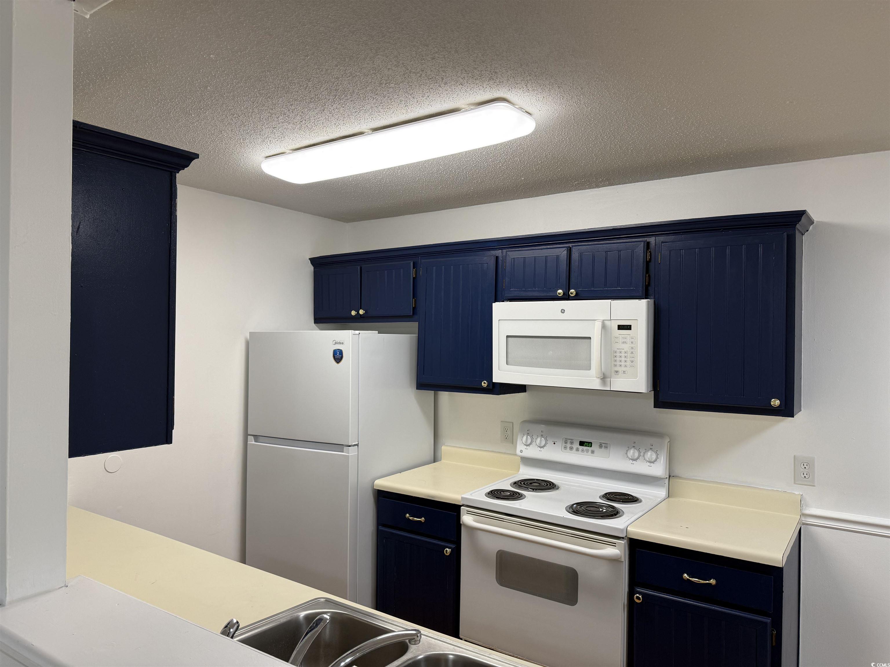 1356 Glenns Bay Road, Unit 206 Surfside Beach, SC 29575 - Photo 11 of 40 Kitchen with blue cabinetry, white appliances, light countertops, and a textured ceiling