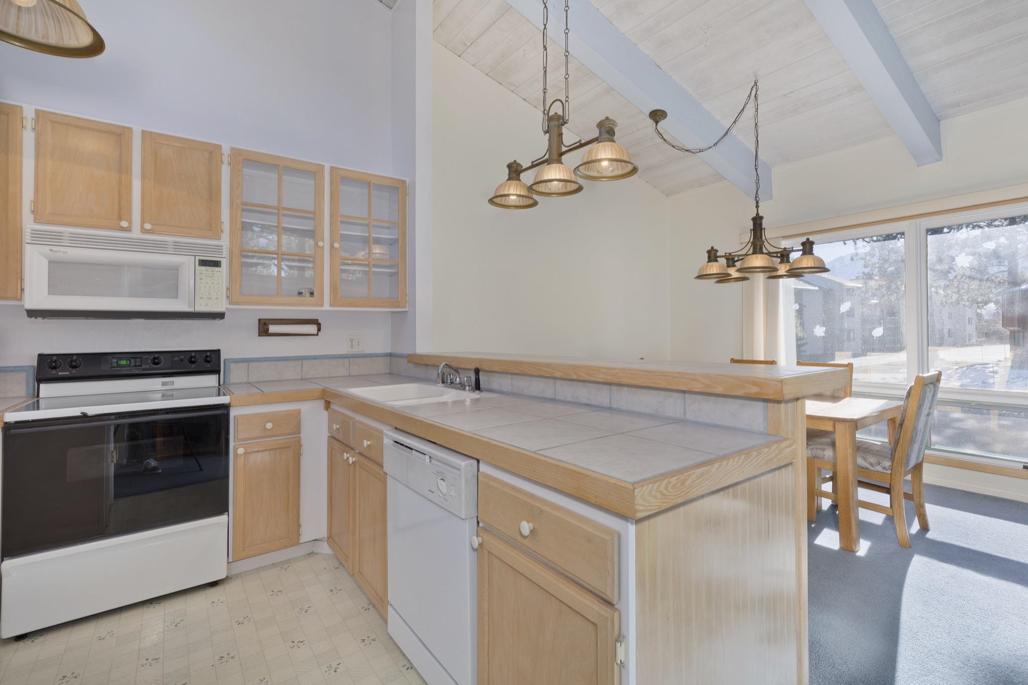 3251 Chateau Road, Unit 40 Mammoth Lakes, CA 93546 - Photo 4 of 31 Kitchen featuring a peninsula, white appliances, light wood finish cabinets, pendant lighting, and a high wooden beamed ceiling