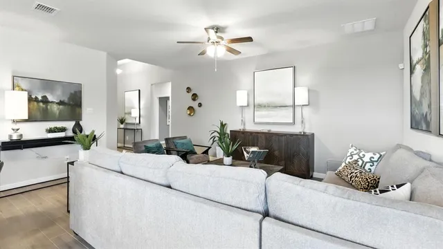 a living room with furniture a chandelier and a dining table with wooden floor