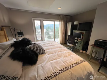 a bedroom with a bed a television and a large window