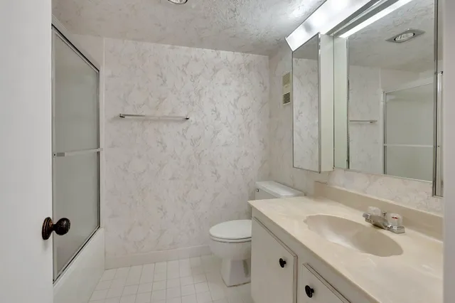 a bathroom with a granite countertop sink a toilet and shower