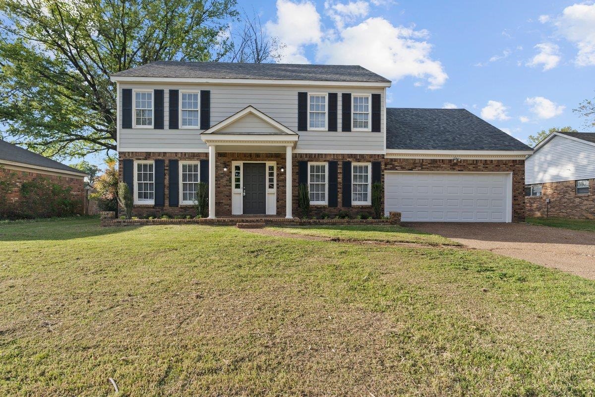 View of front of property featuring brick siding, a front lawn, a garage, and concrete driveway