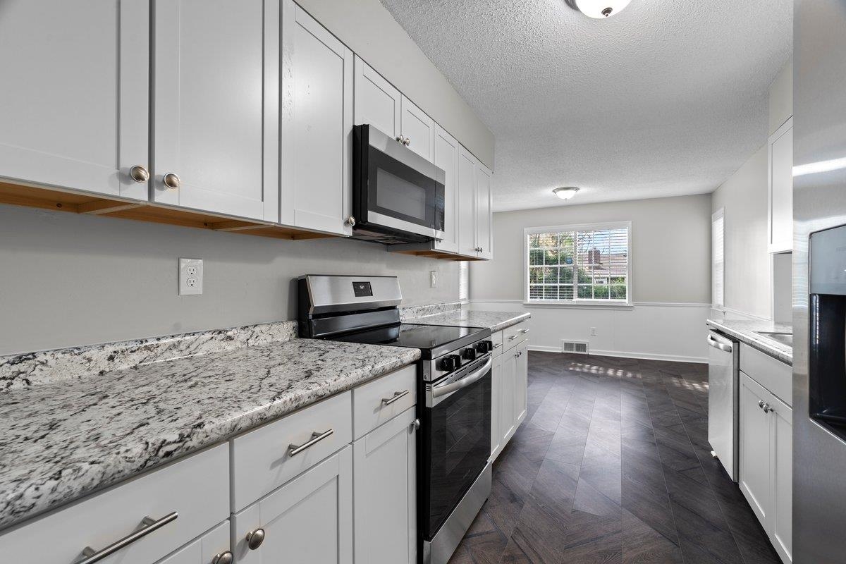 6010 Fox Ridge Drive Memphis, TN 38115 - Photo 13 of 34 Kitchen with stainless steel appliances, a textured ceiling, parquet flooring, white cabinetry, and light stone countertops