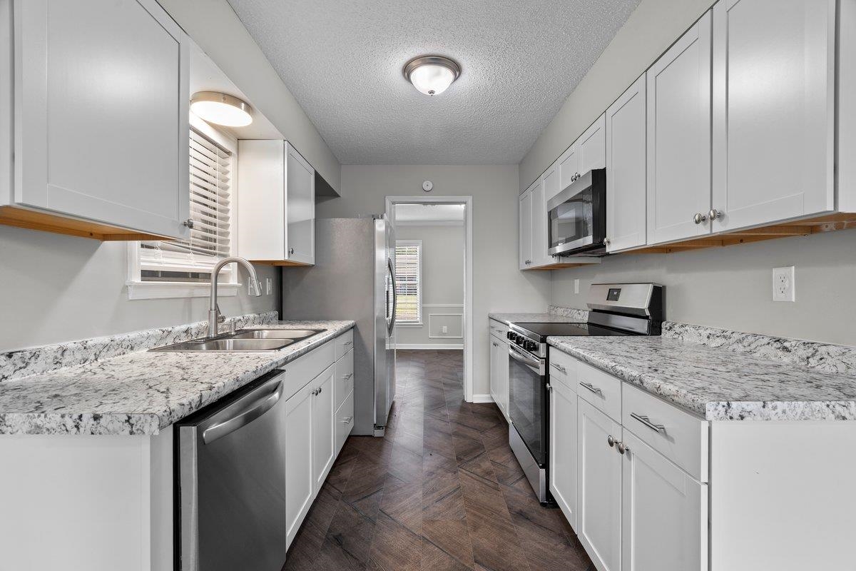 6010 Fox Ridge Drive Memphis, TN 38115 - Photo 15 of 34 Kitchen featuring stainless steel appliances, a textured ceiling, light countertops, white cabinetry, and parquet flooring