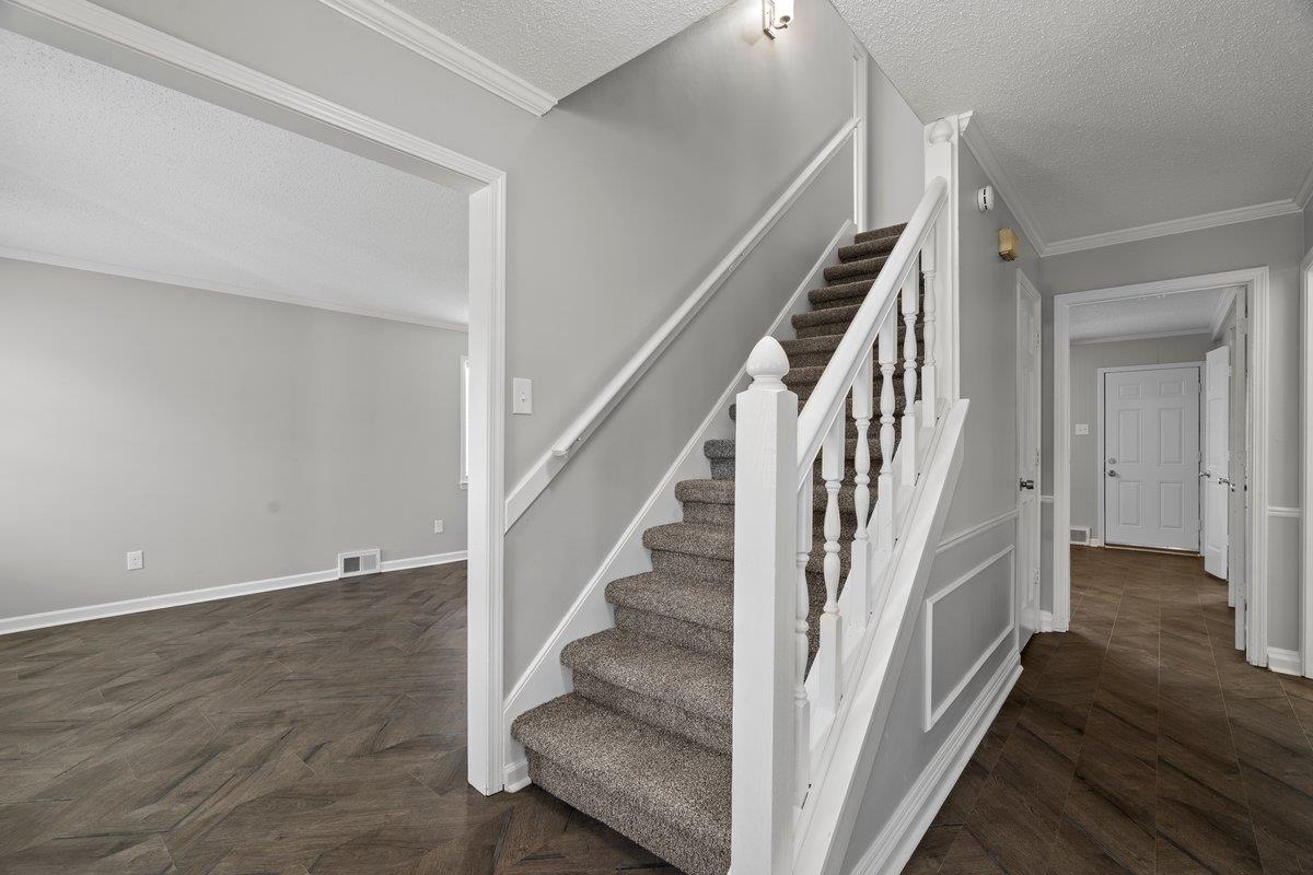 6010 Fox Ridge Drive Memphis, TN 38115 - Photo 20 of 34 Stairs with a textured ceiling, ornamental molding, and wood finished floors