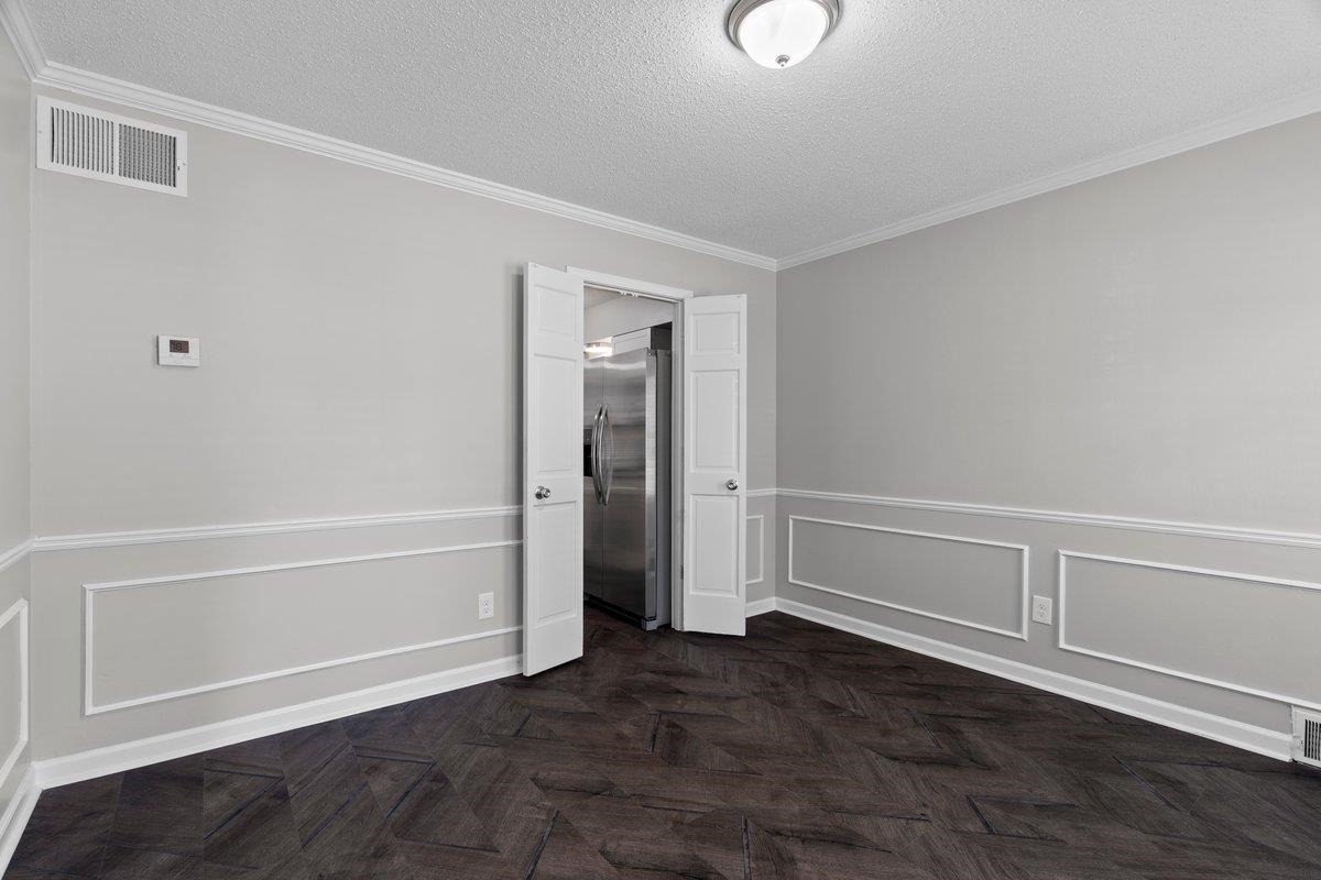 6010 Fox Ridge Drive Memphis, TN 38115 - Photo 9 of 34 Unfurnished bedroom featuring stainless steel refrigerator with ice dispenser, a textured ceiling, parquet floors, ornamental molding, and wainscoting