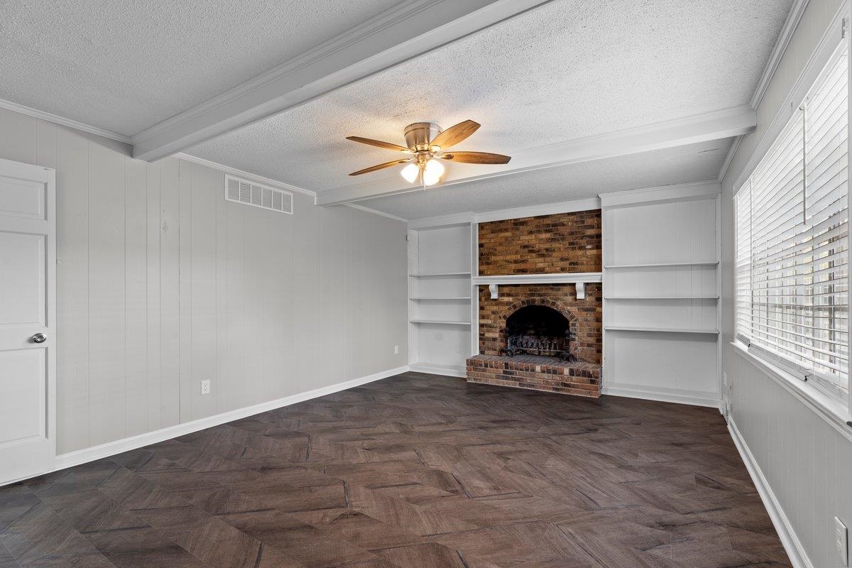 6010 Fox Ridge Drive Memphis, TN 38115 - Photo 10 of 34 Unfurnished living room with a textured ceiling, wood walls, beam ceiling, a ceiling fan, and parquet flooring