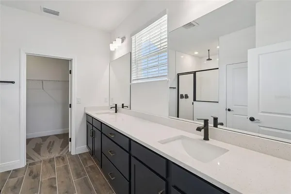 a bathroom with a sink double vanity granite tub shower and a mirror