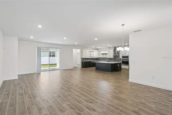 a view of a kitchen with kitchen island a sink wooden floor and black appliances