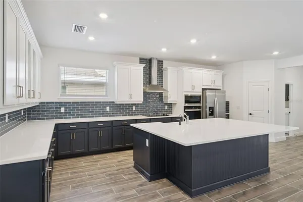 a large kitchen with stainless steel appliances a large counter top and a refrigerator