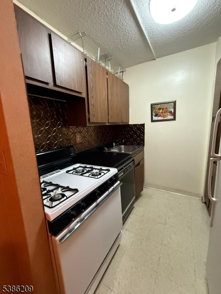 277 Prospect Avenue, Unit H Hackensack, NJ 07601 - Photo 17 of 25 a kitchen with granite countertop a stove and a sink