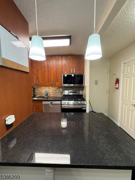277 Prospect Avenue, Unit H Hackensack, NJ 07601 - Photo 4 of 25 a kitchen with kitchen island a stove a sink and a microwave