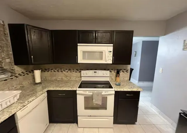a kitchen with granite countertop a sink and a stove top oven