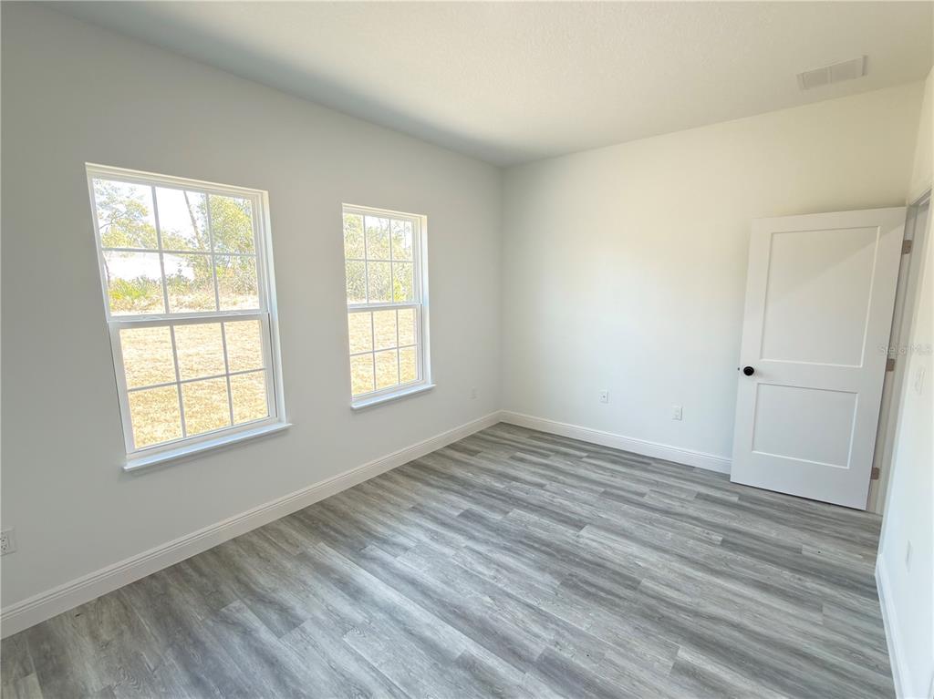 3901 Southwest 161st Loop Ocala, FL 34473 - Photo 32 of 47 an empty room with wooden floor and windows