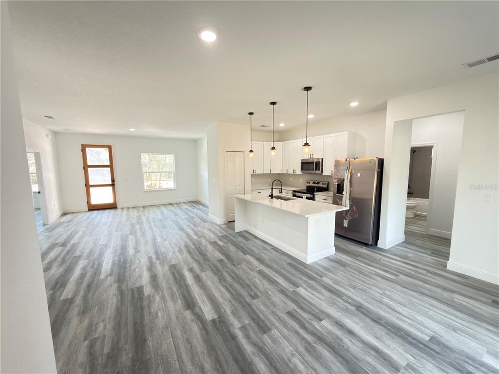 3901 Southwest 161st Loop Ocala, FL 34473 - Photo 6 of 47 a kitchen with stainless steel appliances kitchen island wooden floors and white walls