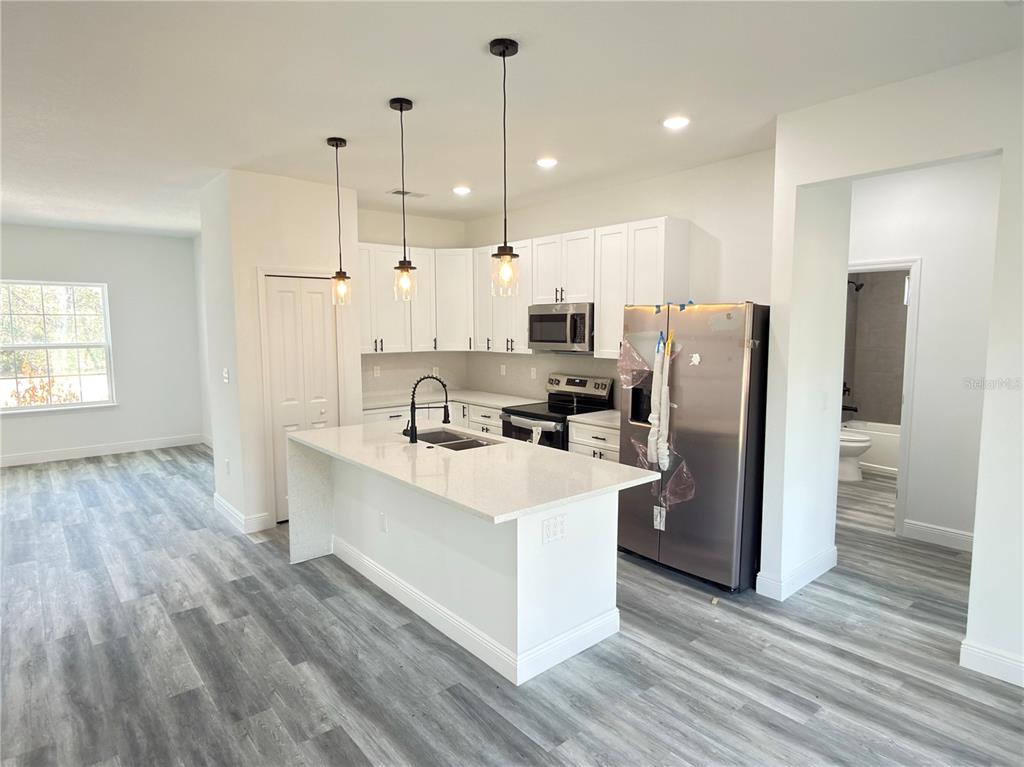 3901 Southwest 161st Loop Ocala, FL 34473 - Photo 7 of 47 a kitchen with stainless steel appliances a refrigerator a sink dishwasher a stove and white countertops with wooden floor