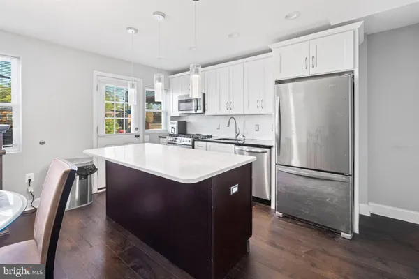 a kitchen with stainless steel appliances a sink a refrigerator and white cabinets