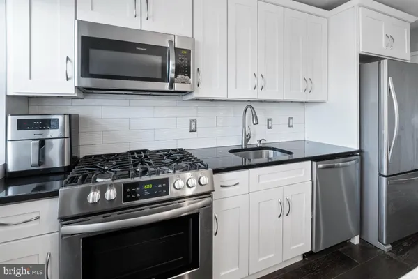 a kitchen with stainless steel appliances granite countertop a stove a microwave and a white cabinets