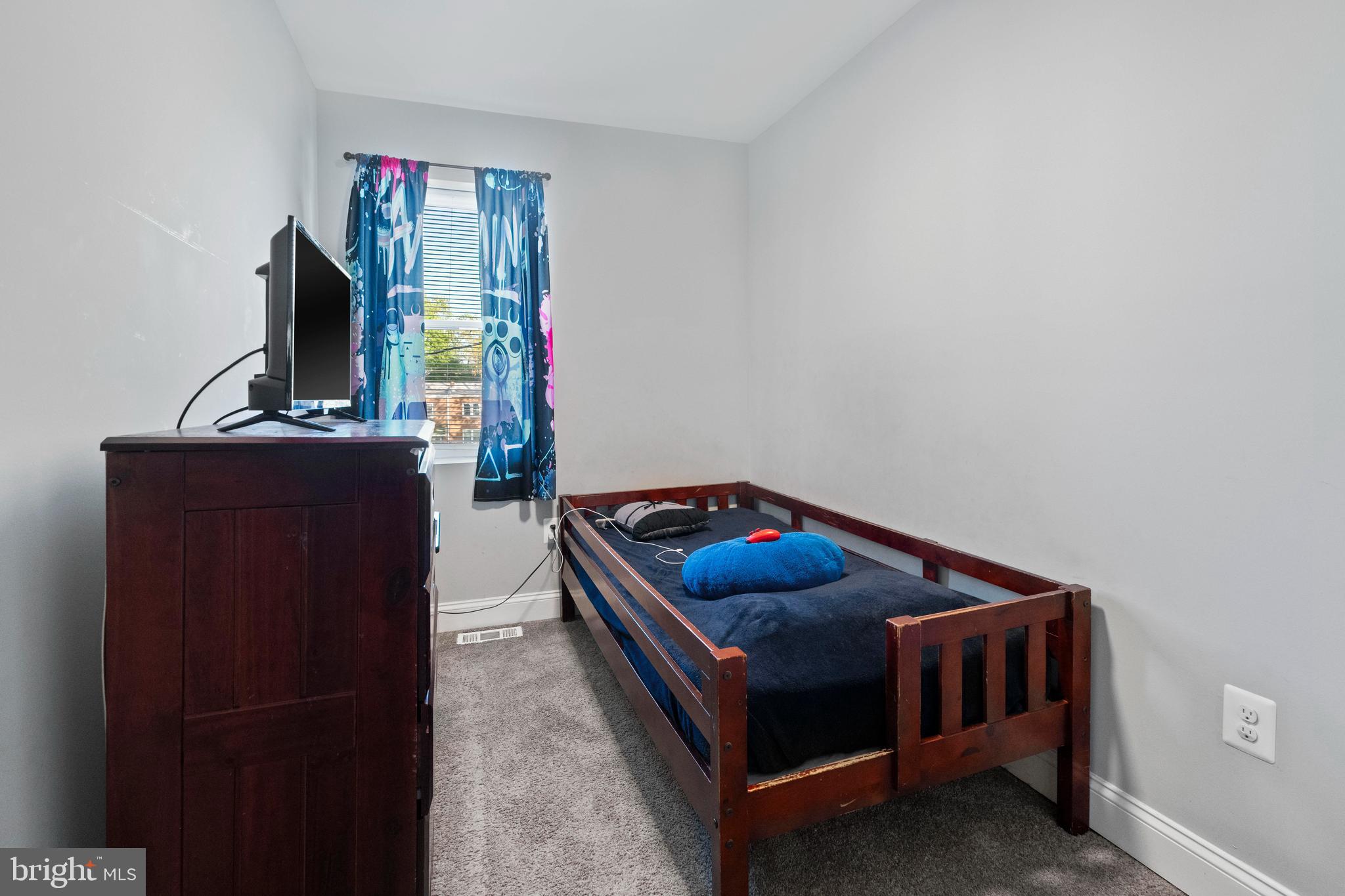 4237 Flowerton Road Baltimore, MD 21229 - Photo 10 of 27 a bedroom with a bed and a flat tv screen on a dresser