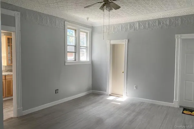 an empty room with wooden floor chandelier fan and windows